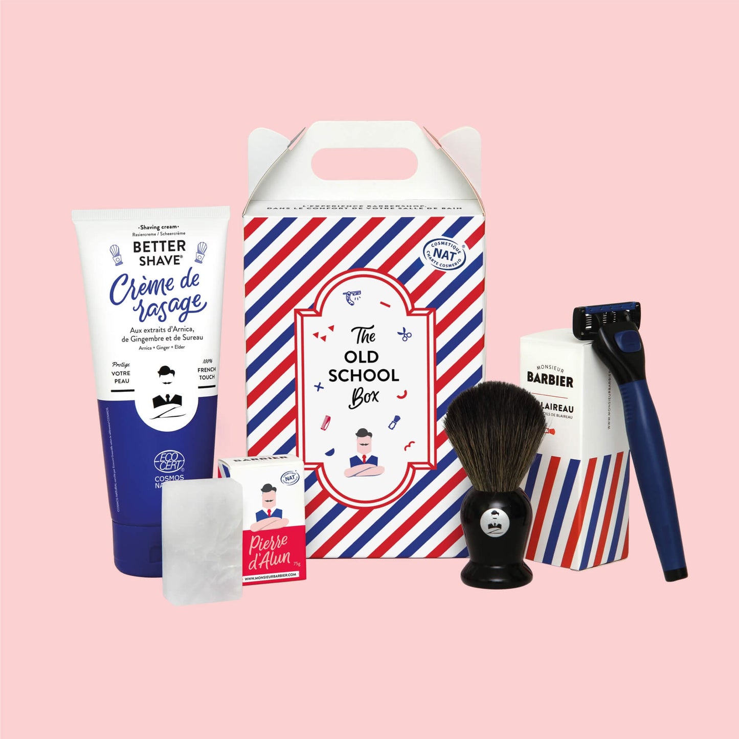 Ensemble de produits de rasage pour homme Monsieur BARBIER OLD SCHOOL BOX, comprenant crème à raser, blaireau, rasoir et pierre d'alun, présentés sur fond rose.