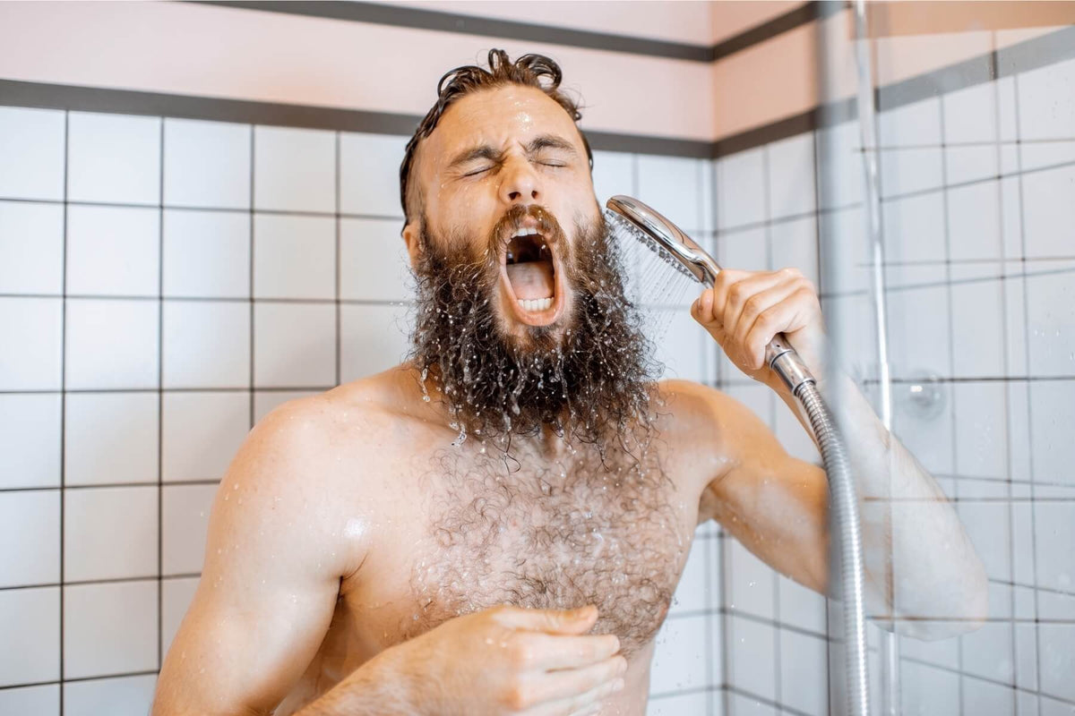 Homme barbu sous une douche froide