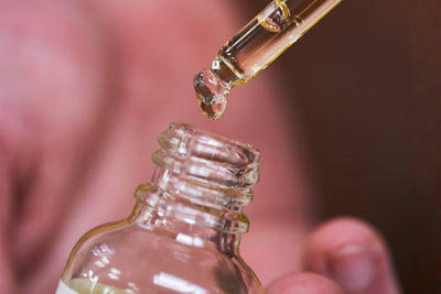 Goutte d'huile de ricin tombant d'une pipette dans son flacon en verre