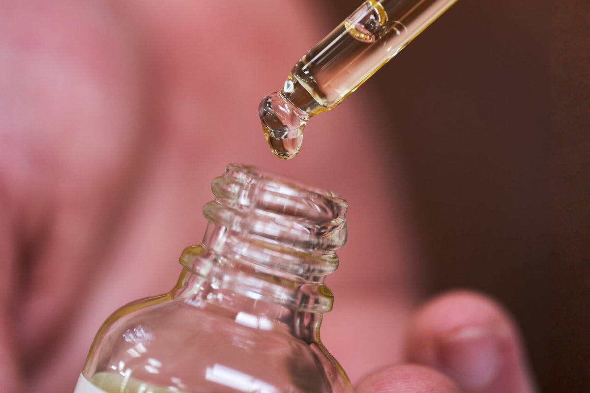 Goutte d'huile de ricin tombant d'une pipette dans son flacon en verre