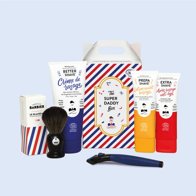 Ensemble complet de rasage SUPER DADDY BOX de Monsieur BARBIER comprenant des tubes de crème de rasage, lotion avant-rasage, après-rasage anti-âge, un blaireau et un rasoir, présenté dans une boîte à rayures bleues et blanches.