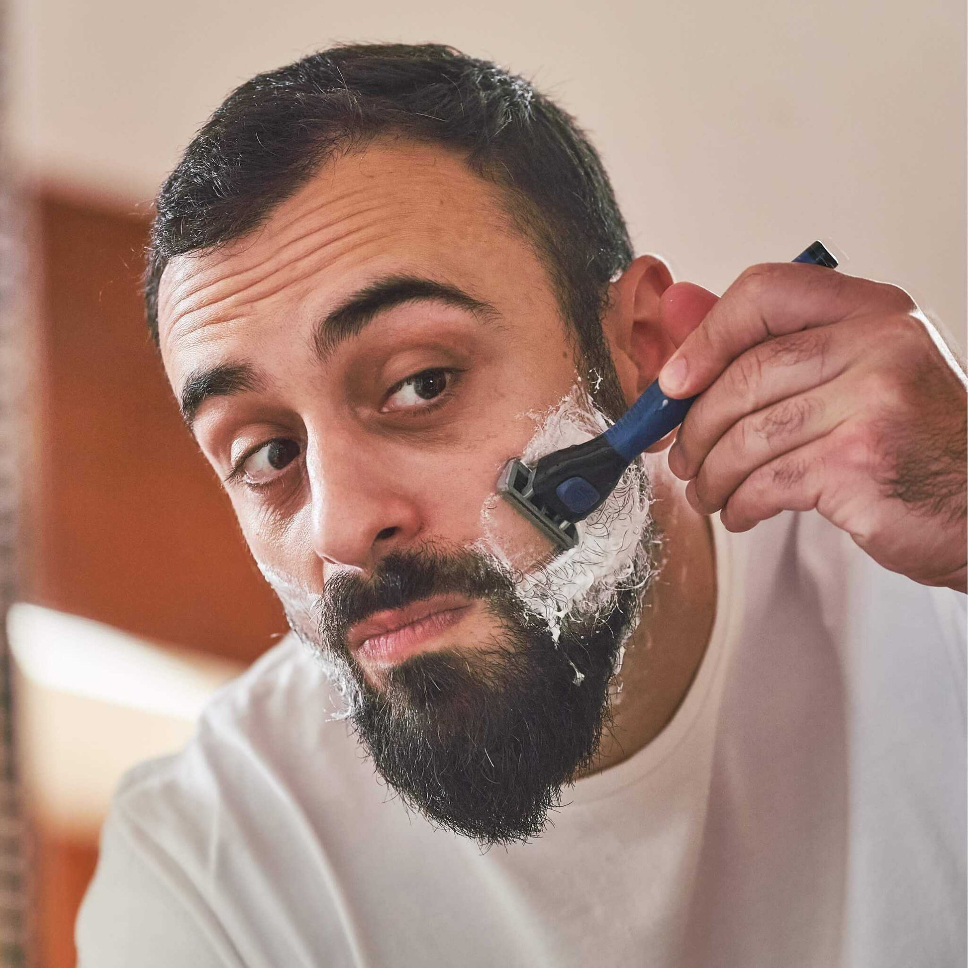 Homme se rasant la joue au rasoir après application du savon de rasage BIO Monsieur BARBIER BETTER SHAVE, mousse dense et glisse optimale.